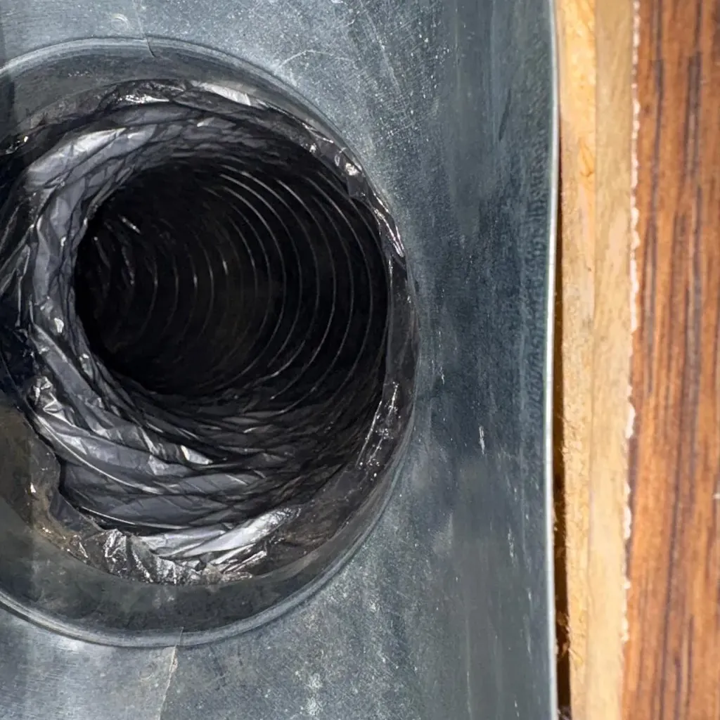 Air duct cleaning in New Windsor, NY: example job photo of a register boot with the flexible duct behind it