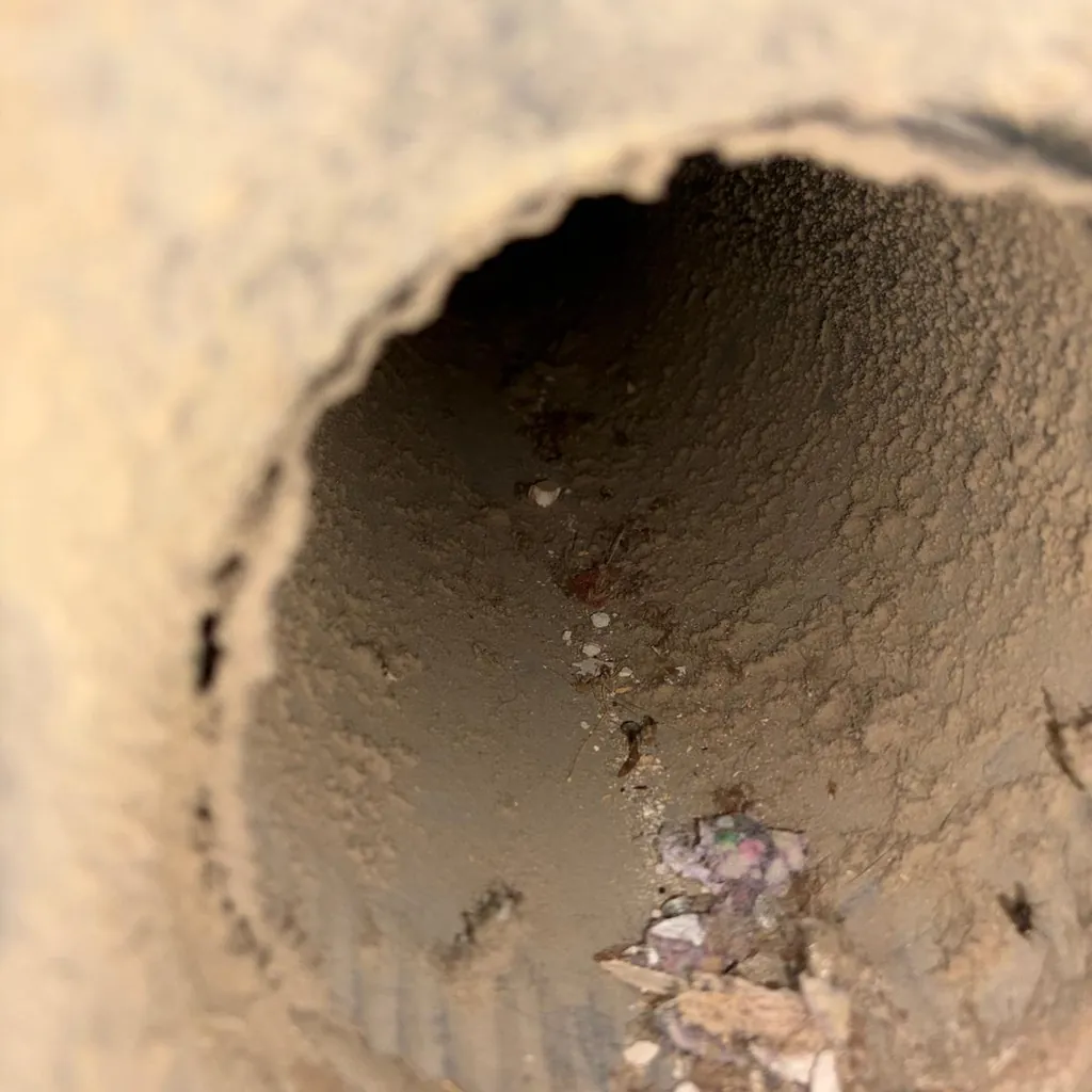 A round duct collar with dust and debris before cleaning
