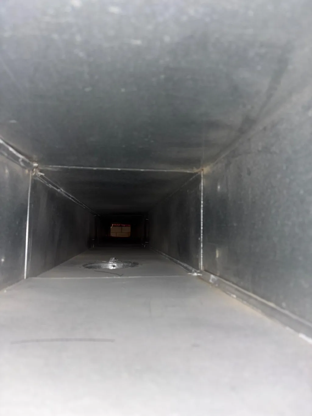 The same rectangular supply duct after cleaning, bare metal along the bottom