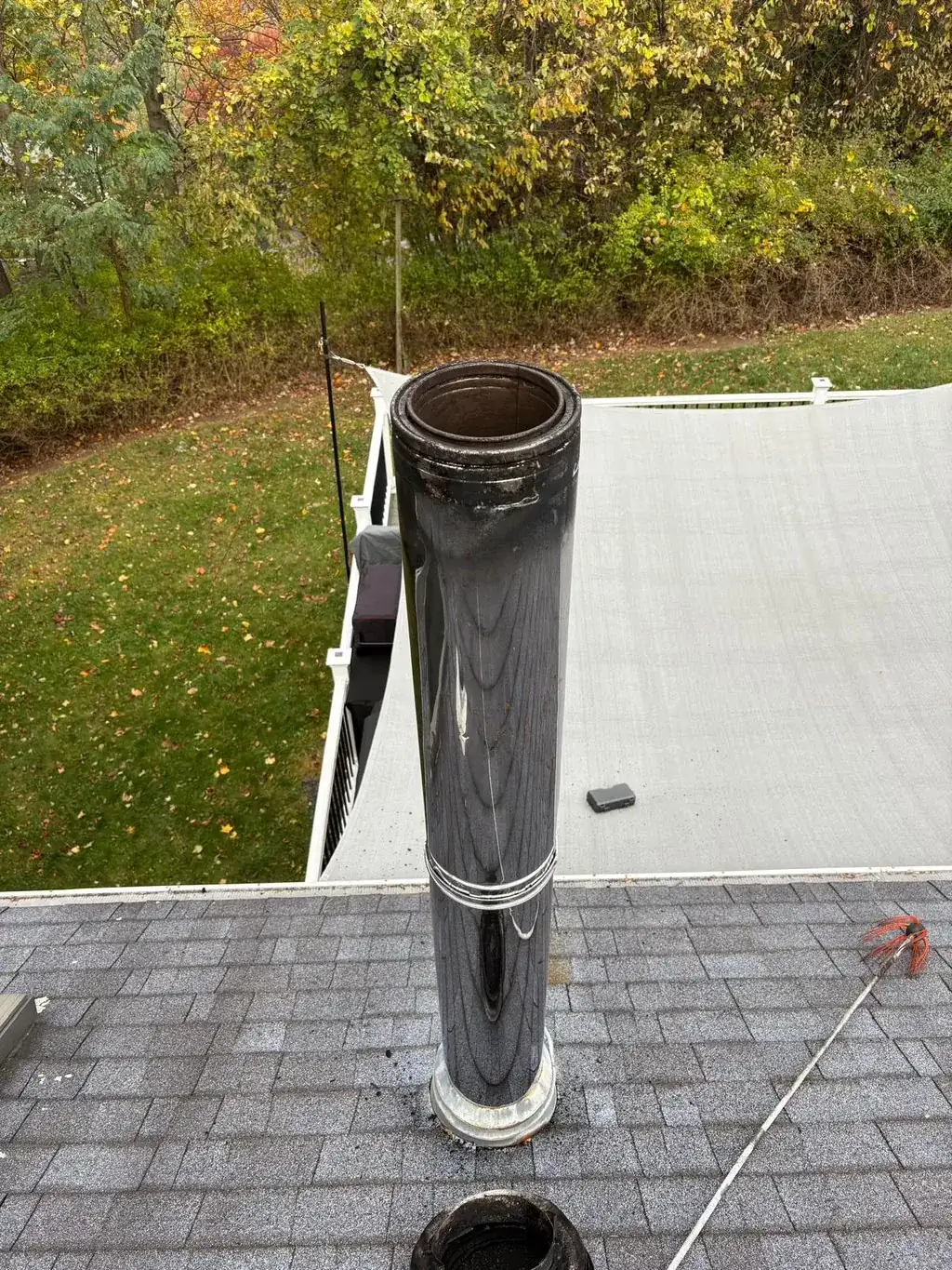 Stainless chimney cap fitted over a round flue on a flat roof
