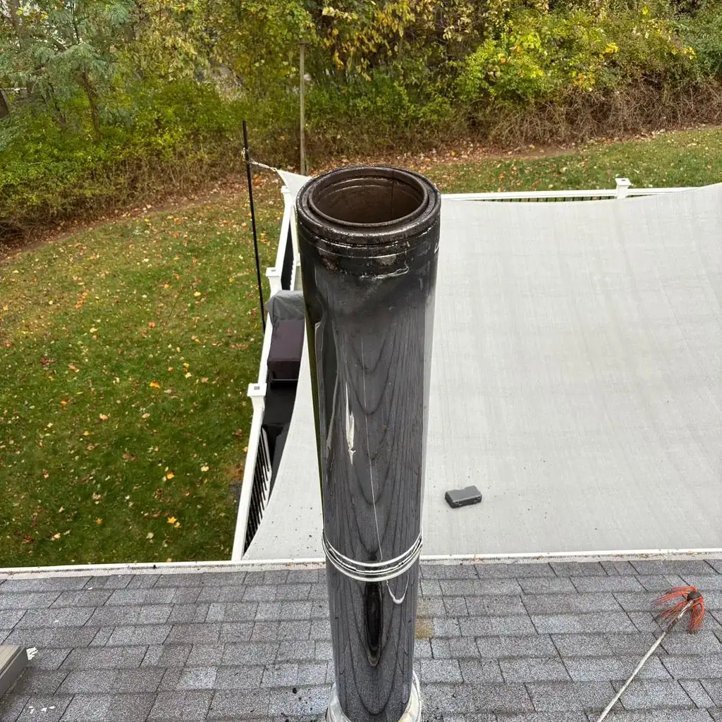Stainless chimney cap fitted over a round flue on a flat roof