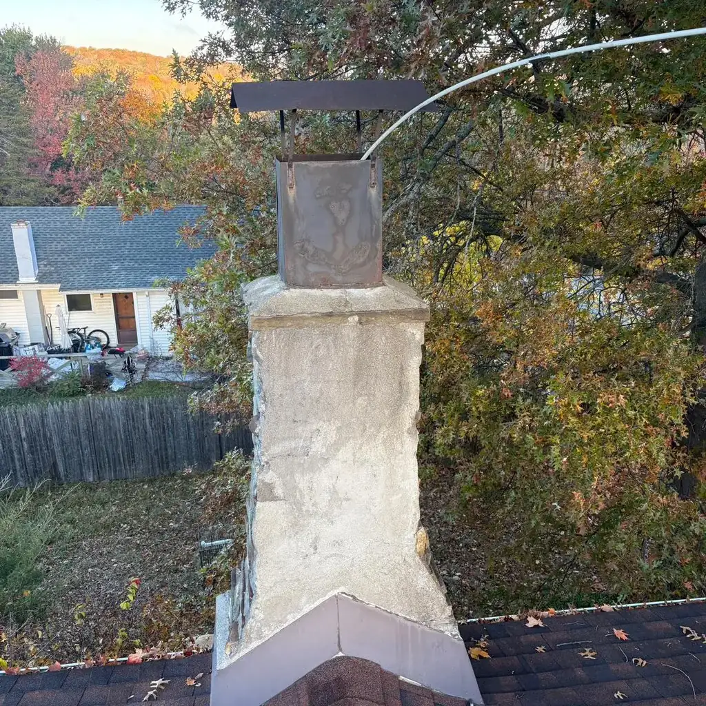 Stucco chimney top with metal flashing at the roof line