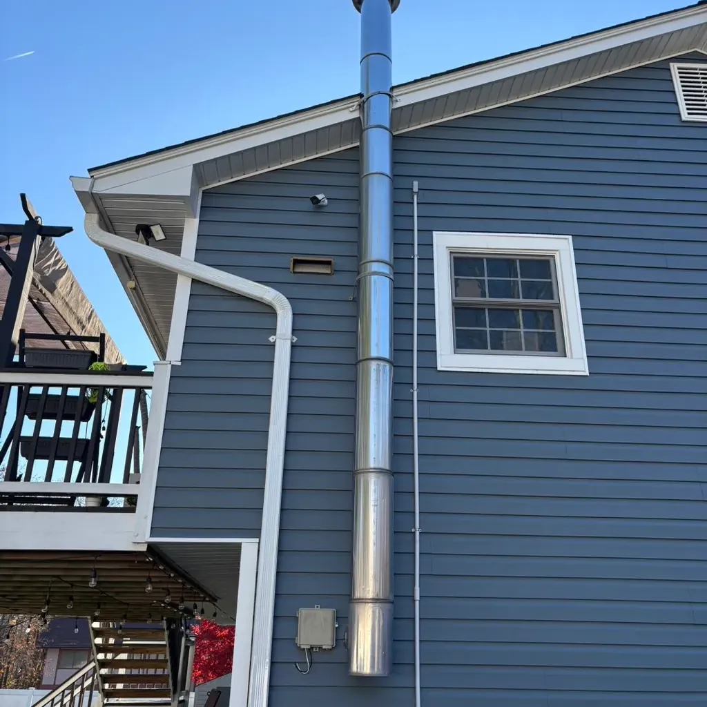 Stainless flue running up an outside wall with a cap on top