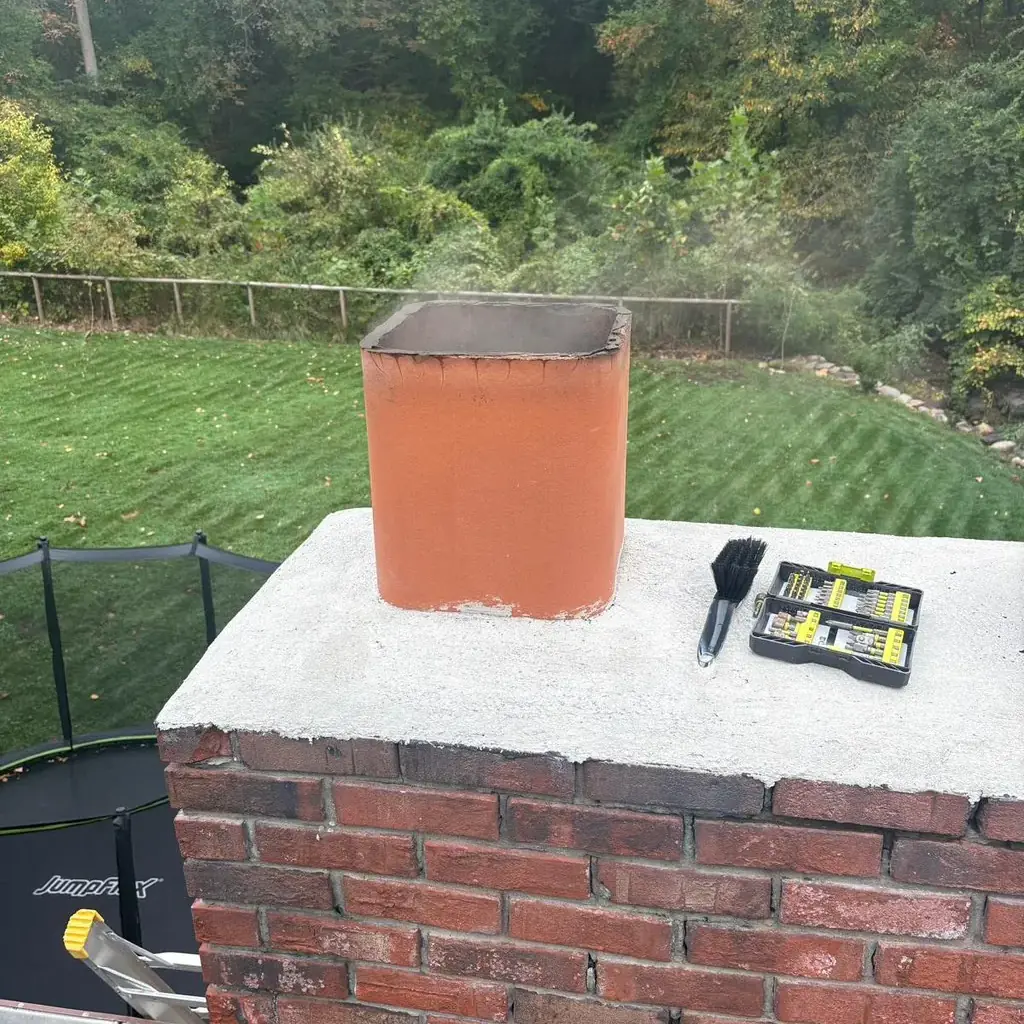 Bare clay flue tile with no cap, on a brick chimney crown