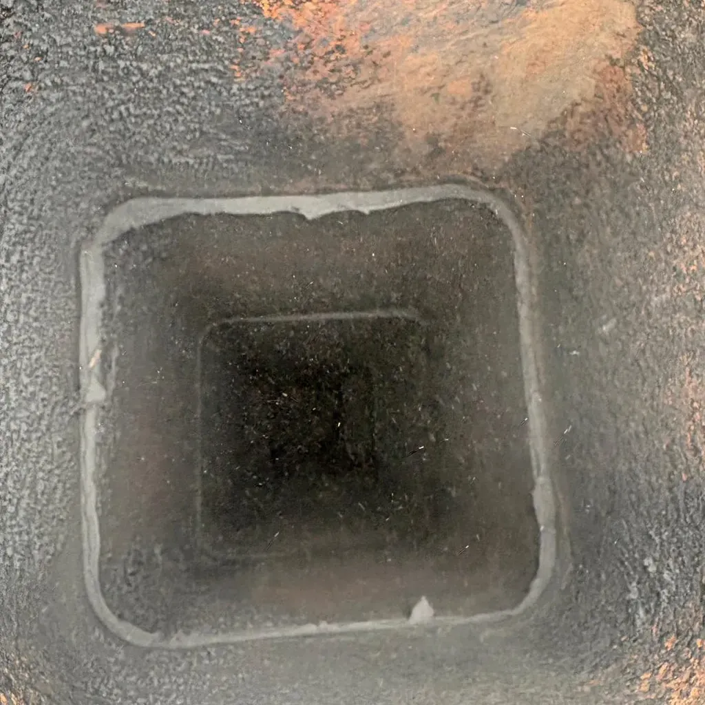 Looking down a square clay tile flue from the chimney top