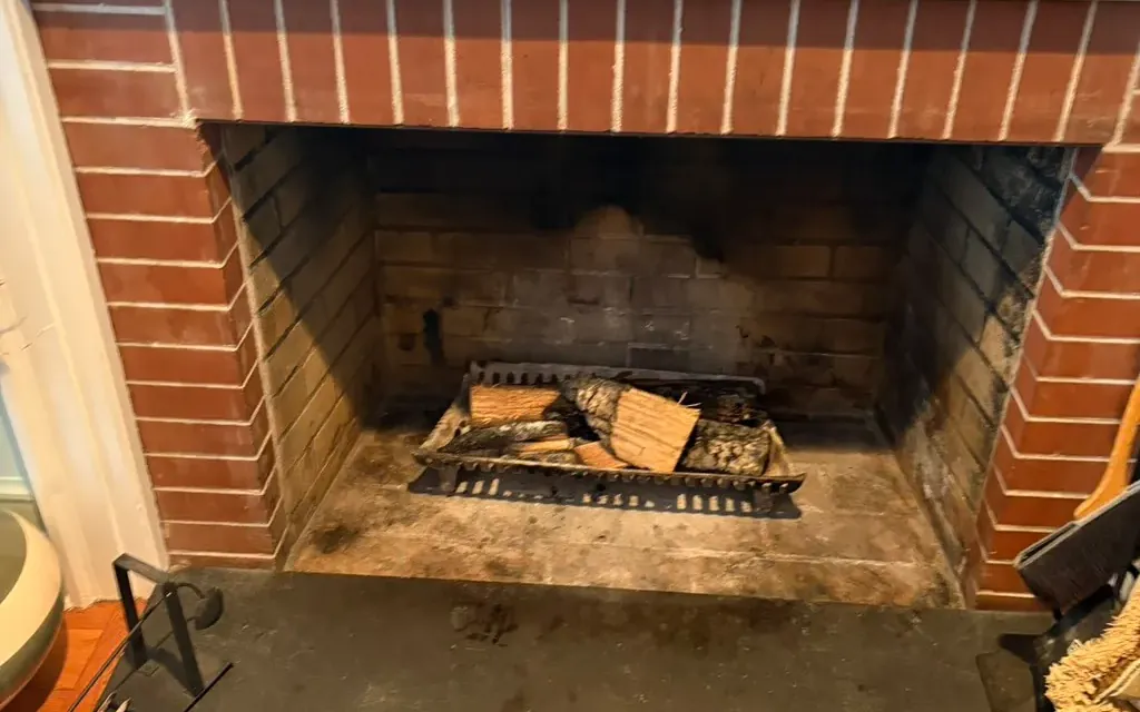 Chimney sweep in progress, the vacuum hose in the firebox of a brick fireplace
