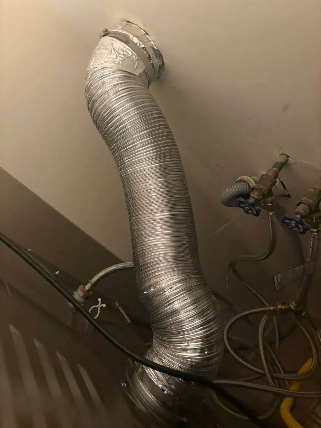 New metal dryer duct running up the wall beside the gas line