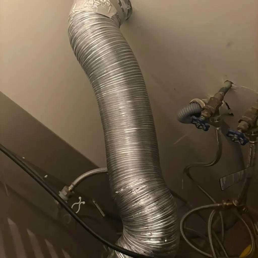 New metal dryer duct running up the wall beside the gas line