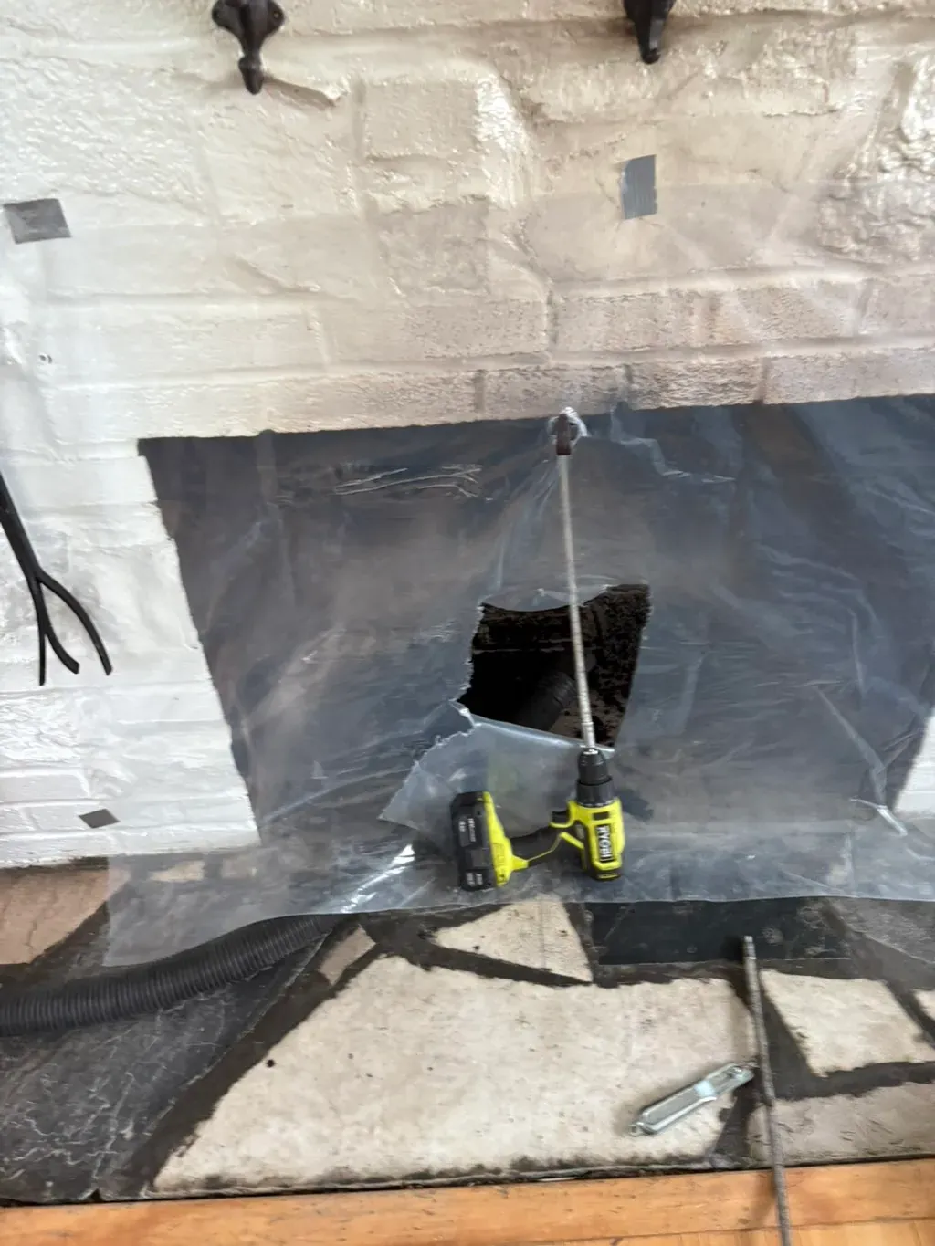 Chimney sweeping: the fireplace sealed with sheeting while the rod goes up the flue