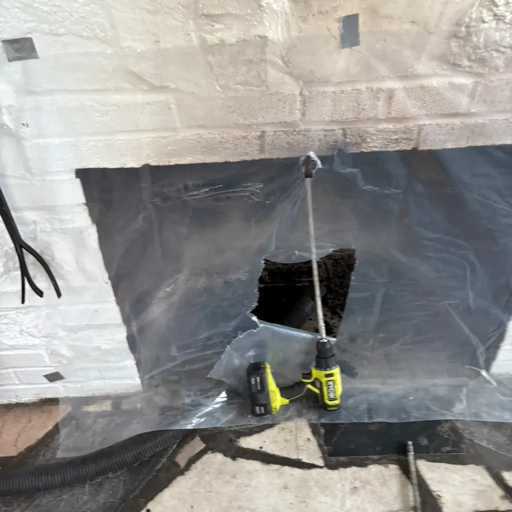 Chimney sweeping: the fireplace sealed with sheeting while the rod goes up the flue