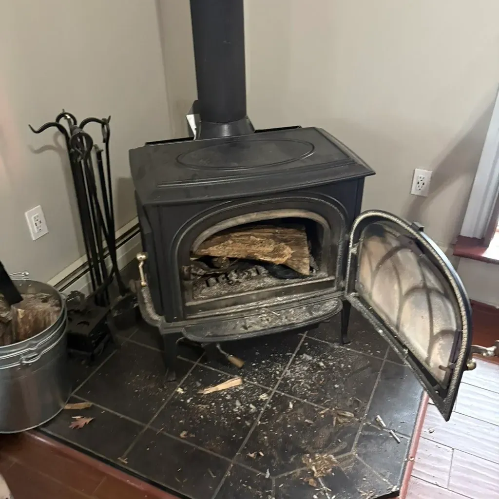 Wood stove with its door open for cleaning